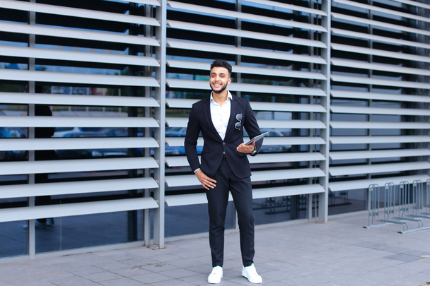 Arabic guy in business center stands smiling - Foto, afbeelding
