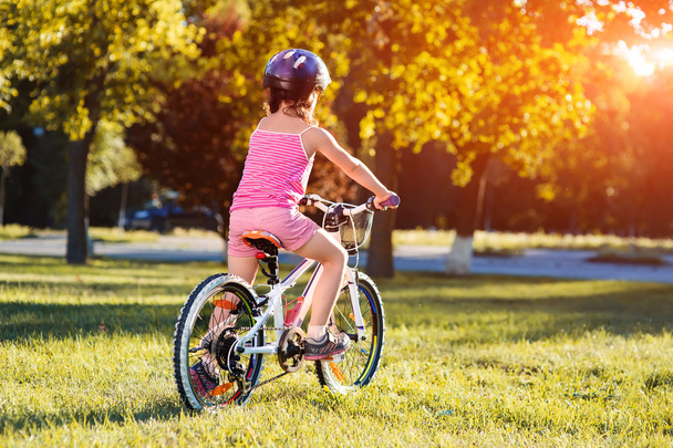 child girl riding bicycle on summer sunset in the park. - Fotografie, Obrázek