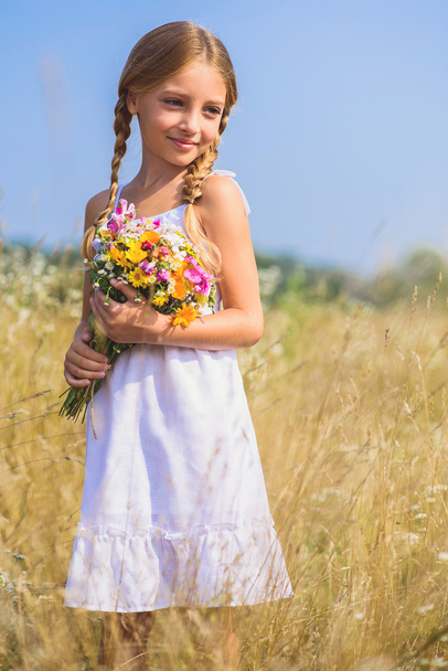 Cute female kid with flowers in meadow - Фото, изображение