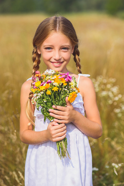 Happy child with bouquet on field - Zdjęcie, obraz
