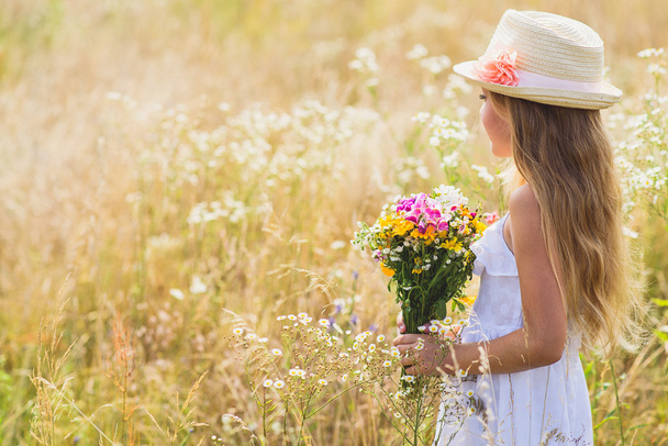 Cute female kid with flowers on meadow - Foto, imagen