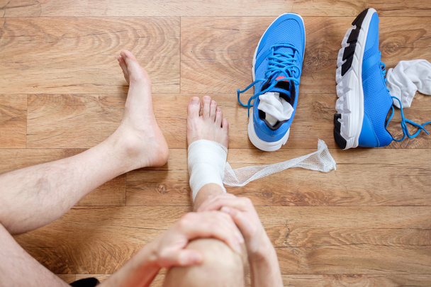 deportista masajeando su tobillo lesionado después de un accidente deportivo
 - Foto, imagen