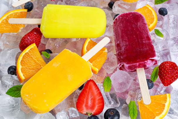 refrescantes paletas de paletas de frutas sobre fondo de hielo con bayas, menta
. - Foto, Imagen