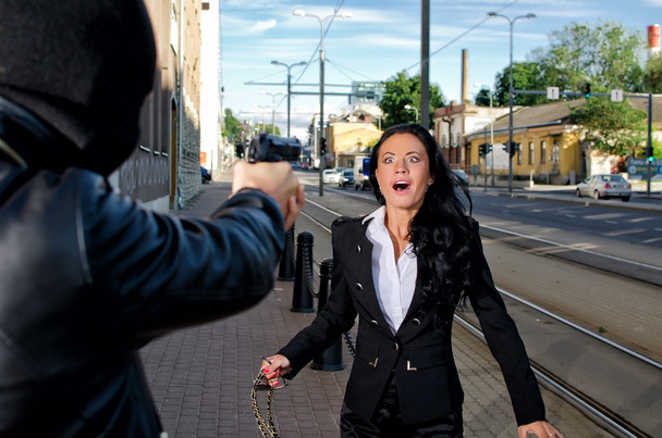 Bandit avec une arme menaçant une jeune femme dans la rue
 - Photo, image