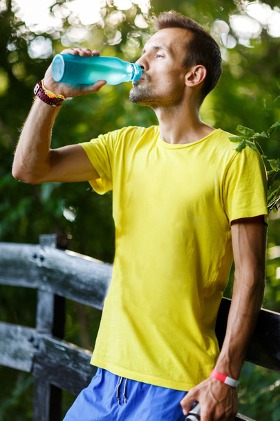 Young athlete drinking water in park - Fotoğraf, Görsel