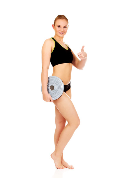 Young athletic woman holding balance board and shows thumb up - Foto, Imagen