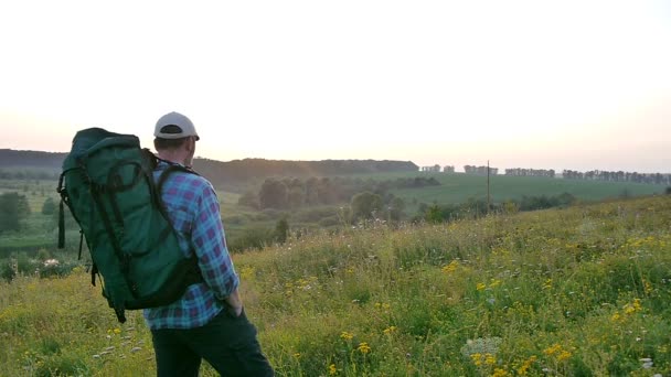 A bearded man with a backpack walking in the field - Séquence, vidéo