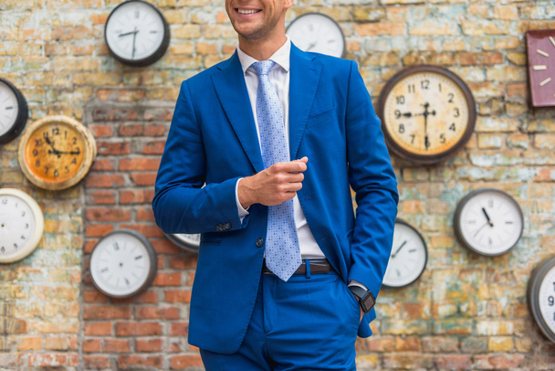 Man in suit standing near wall with clocks - Valokuva, kuva