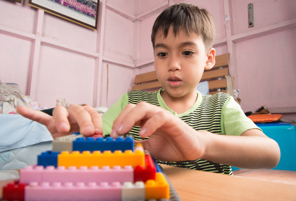 Маленький хлопчик грає в пластиковий блок будівництва внутрішньої активності освіти
 - Фото, зображення