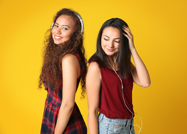 Beautiful girls listening music on yellow background - Foto, Bild