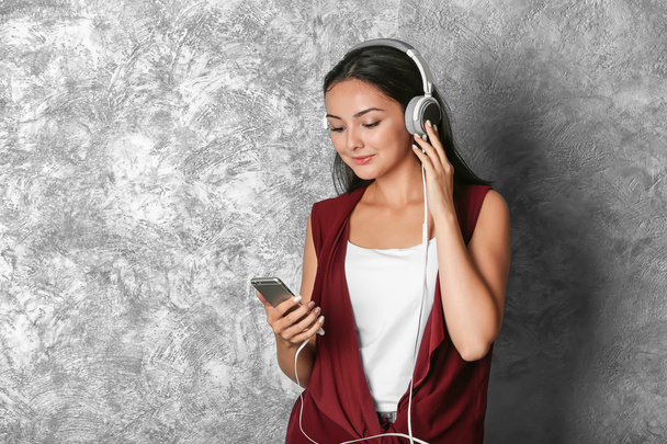 Beautiful girl listening music on grey background - Zdjęcie, obraz