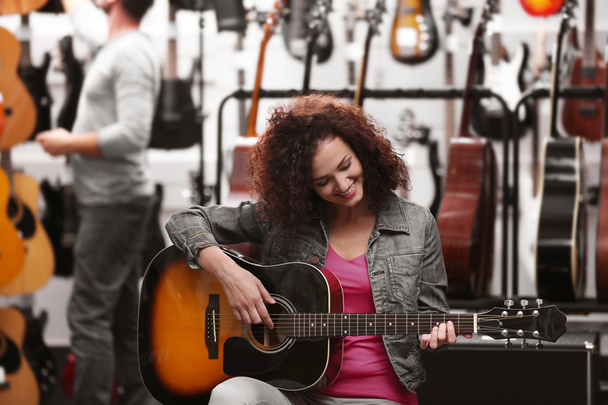Beautiful girl playing guitar in music shop - Fotoğraf, Görsel