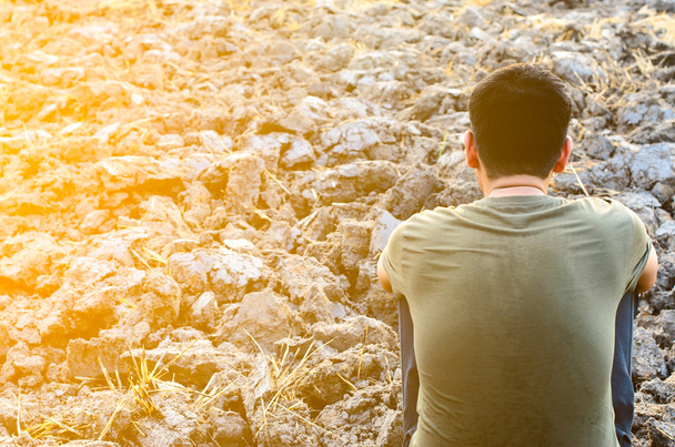 Turhautunut ja surullinen nuori mies istuu karussa maassa. auringonvalon kanssa
 - Valokuva, kuva