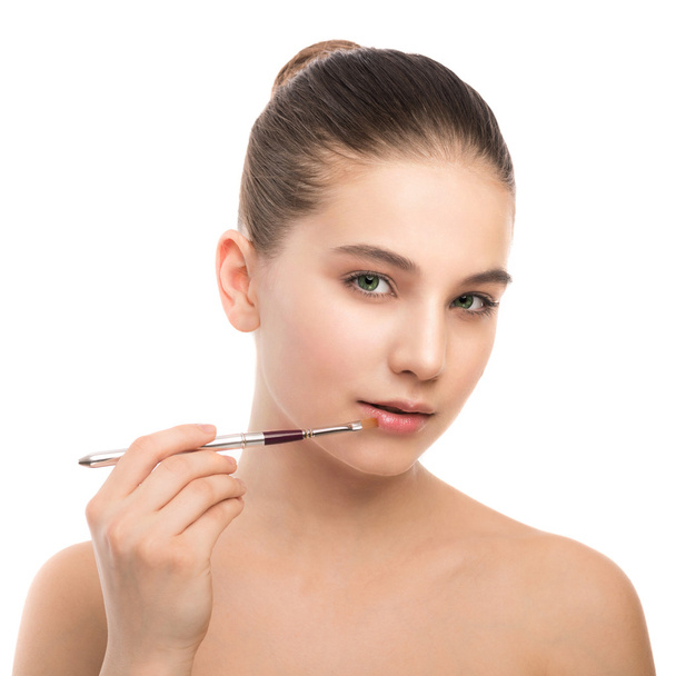 Young brunette woman with clean face. Girl perfect skin applying cosmetic brush. Isolated on a white. - Photo, Image