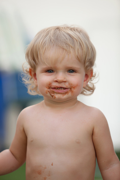 Bebê feliz com um rosto sujo depois de comer chocolate
  - Foto, Imagem