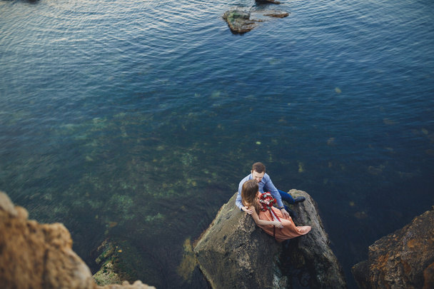 Wedding couple kissing and hugging on rocks near blue sea - Foto, Imagen