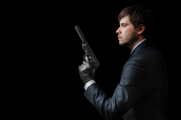 Murderer or assassin holding pistol with silencer. Mafia and crime concept. Low key photo. - Photo, Image