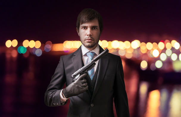 Agent or spy with gun at night. Crime concept. - Photo, Image