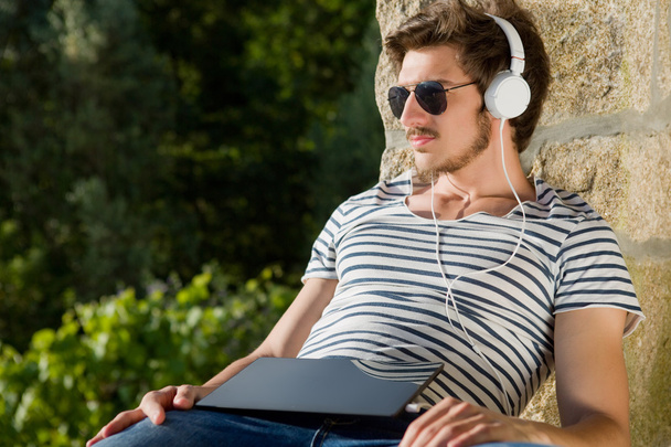 fiatal férfi pihentető egy tablet pc hallgat zenét a fejhallgató - Fotó, kép
