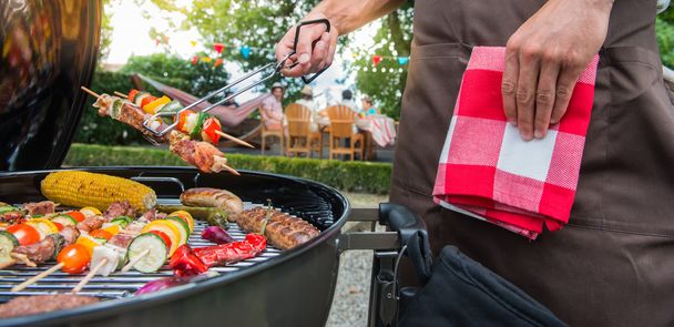 Man grilling meat on garden barbecue party - Φωτογραφία, εικόνα