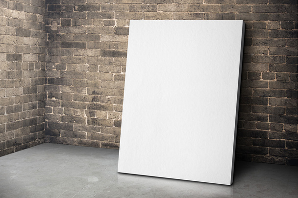 Blank white canvas frame leaning at grunge brick wall and wood - 写真・画像