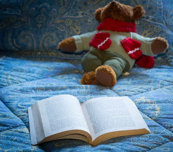 χαρτόδετο βιβλίο ανοιχτό σε κρεβάτι με αρκουδάκι - Φωτογραφία, εικόνα