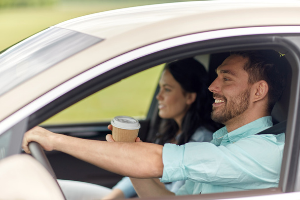 happy man and woman driving in car with coffee - Фото, зображення
