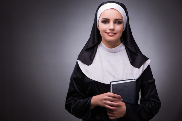 Religieuze nun in religie concept tegen de donkere achtergrond - Foto, afbeelding