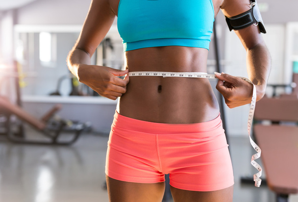 woman measuring waist in gym - Photo, Image