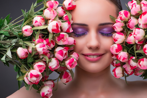 Νεαρή γυναίκα με λουλούδια στην έννοια της ομορφιάς - Φωτογραφία, εικόνα