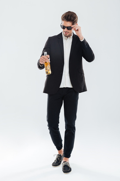 Handsome serious businessman in black sunglasses holding beer bottle - Fotó, kép
