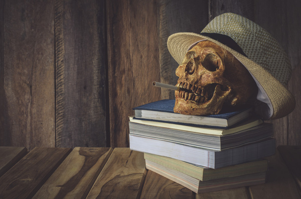Still life skull . Cap machine weave and books on wooden background - Photo, Image