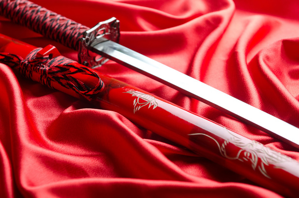 Espada japonesa takana sobre fondo satinado rojo
 - Foto, imagen