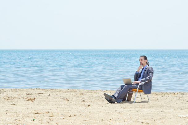 Uomo d'affari che lavora su laptop in riva al mare
 - Foto, immagini