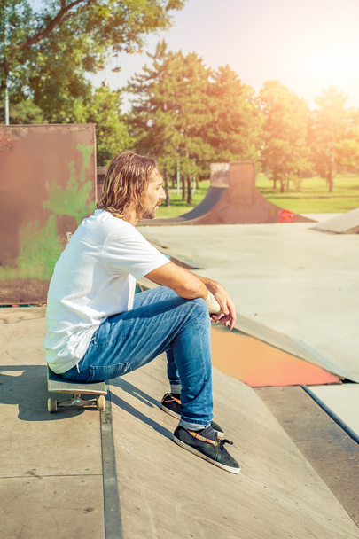 A young skater resting on his board - Fotoğraf, Görsel