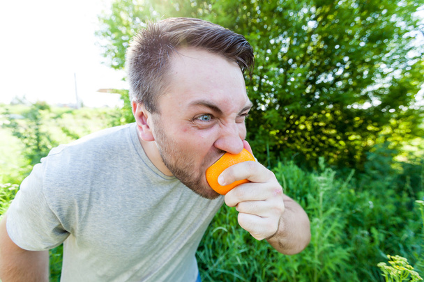 hombre comiendo naranja al aire libre
 - Foto, Imagen