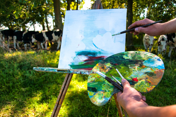 Az ember festeni egy képet a tehenek a szabadban - Fotó, kép