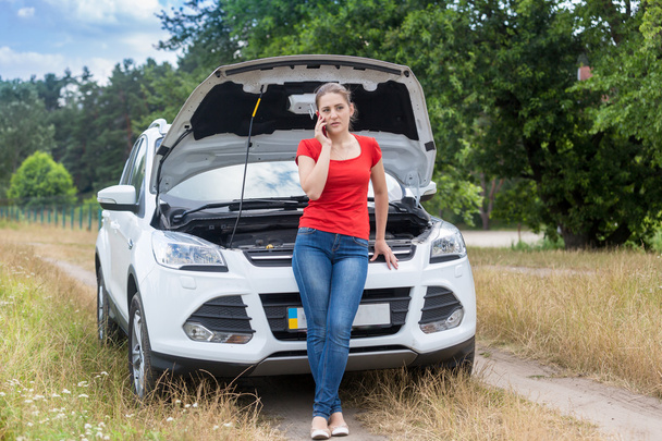 Mujer frustrada apoyándose en coche roto en el campo y pidiendo
  - Foto, Imagen