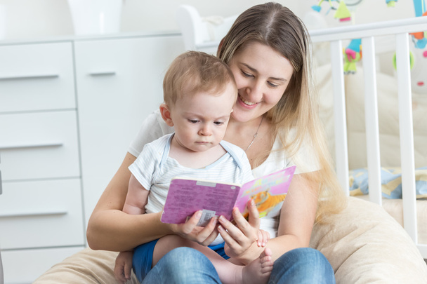 Beautiful smiling mother reading book to her 9 months old baby b - Φωτογραφία, εικόνα