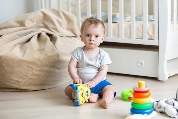 Baby boy playing on floor with colorful toy car - Foto, afbeelding