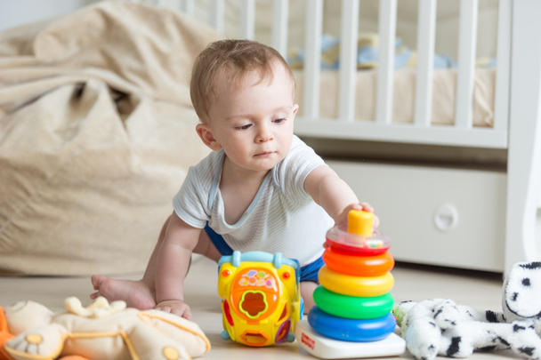 Portret van 10 maanden oude baby spelen met kleurrijke speelgoed toren - Foto, afbeelding