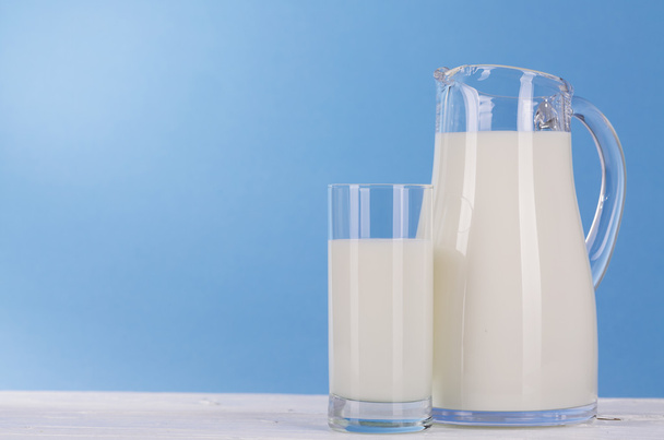Кувшин и стакан молока на синем фоне
. - Фото, изображение