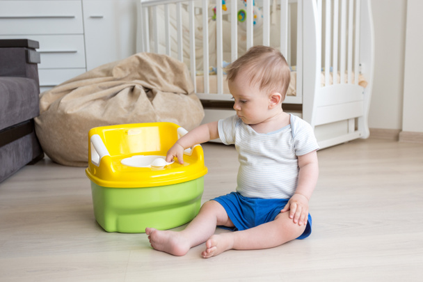 10 maanden oude babyjongen krijgen gewend aan het gebruik van de kamer pot - Foto, afbeelding