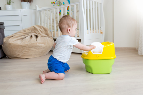 10 mesi bambino ragazzo cercando di sedersi su camera pot
 - Foto, immagini