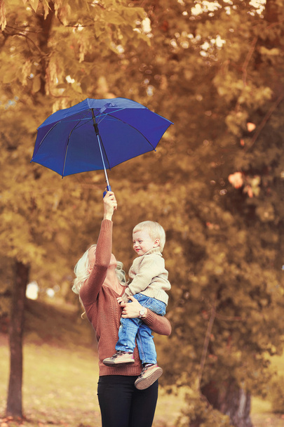 Happy family mother and child with umbrella in autumn day - Valokuva, kuva