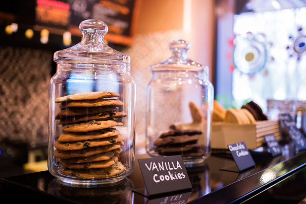 Trufa de biscoitos de baunilha com chocolate em frascos de vidro nas prateleiras do café. Foco seletivo
 - Foto, Imagem
