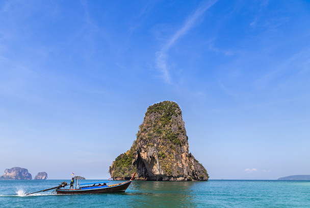 Лодка в Андаманском море с известняковым скальным фоном на железнодорожном пляже в Таиланде
 - Фото, изображение