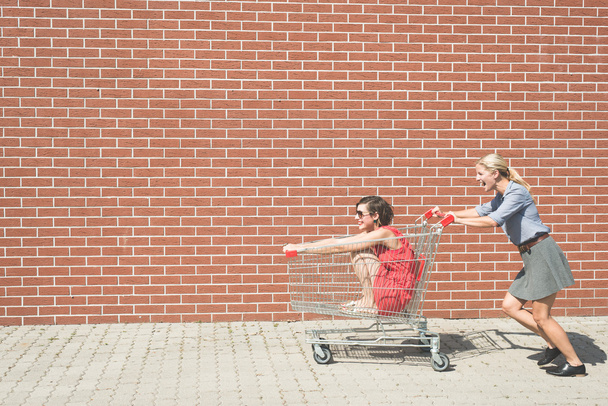 girls having fun with a shopping cart - Photo, Image