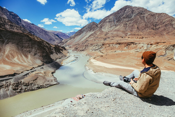Young happy man sitting on the cliff on the trip in Indus River in Leh, Ladakh, India - Фото, изображение