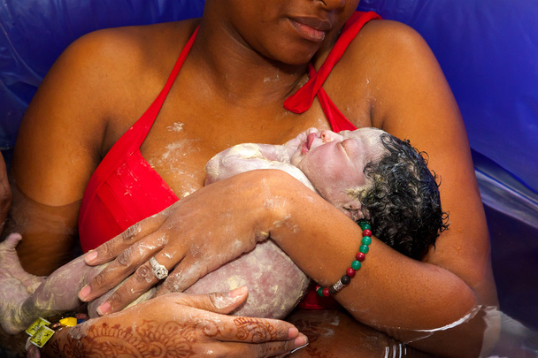 Madre sosteniendo a su bebé recién nacido después de un parto en casa
 - Foto, Imagen